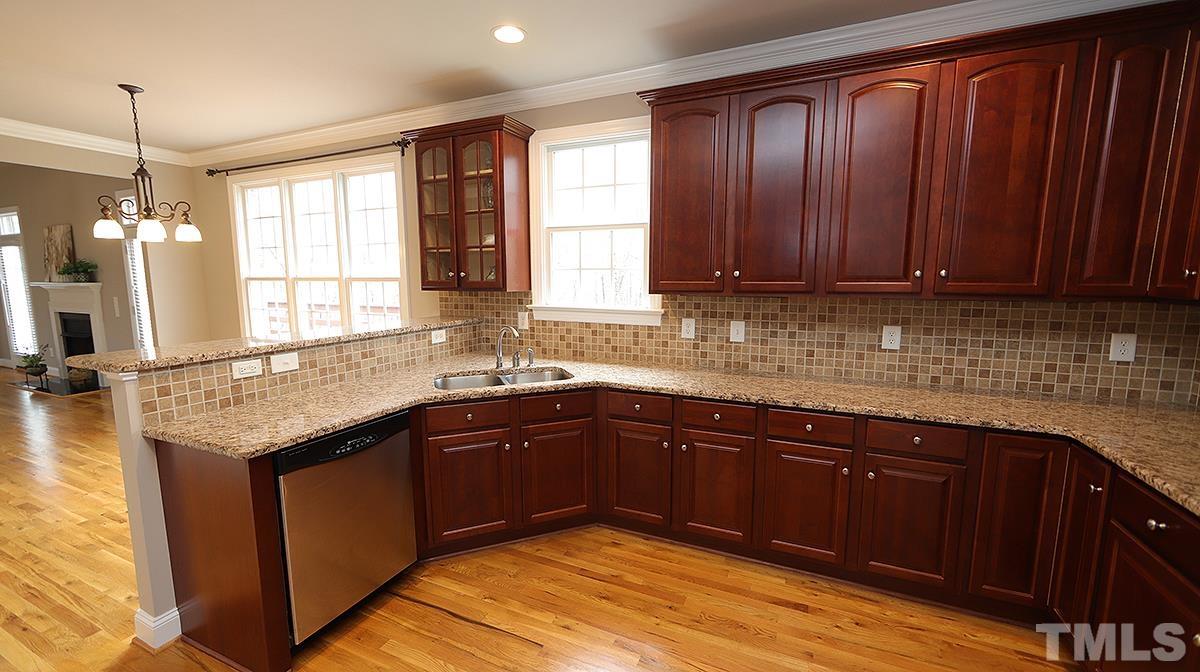 152 Rivers Edge Court Timberlake, NC 27583 - Photo 36 of 41 a kitchen with stainless steel appliances granite countertop wooden cabinets a sink and dishwasher with wooden floor