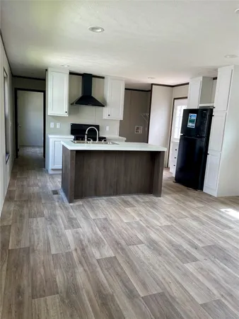 a view of kitchen and empty room with wooden floor