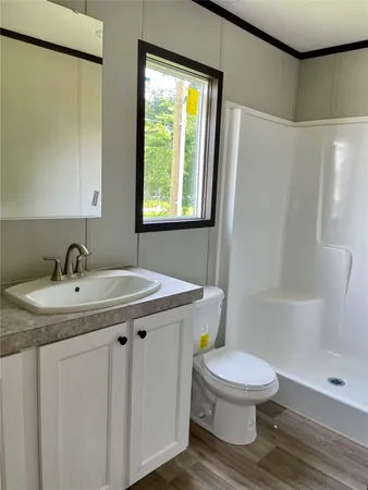 a bathroom with a granite countertop sink toilet a mirror and shower