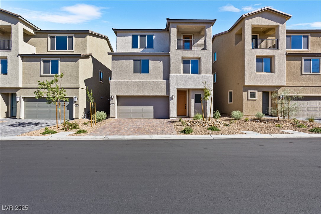 5670 Spring Trellis Street Las Vegas, NV 89113 - Photo 16 of 23 View of front of house featuring stucco siding, decorative driveway, an attached garage, and a balcony