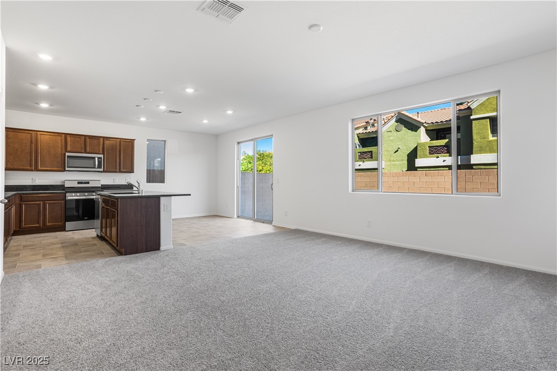 5670 Spring Trellis Street Las Vegas, NV 89113 - Photo 22 of 23 Kitchen with open floor plan, light colored carpet, a kitchen island with sink, appliances with stainless steel finishes, and recessed lighting