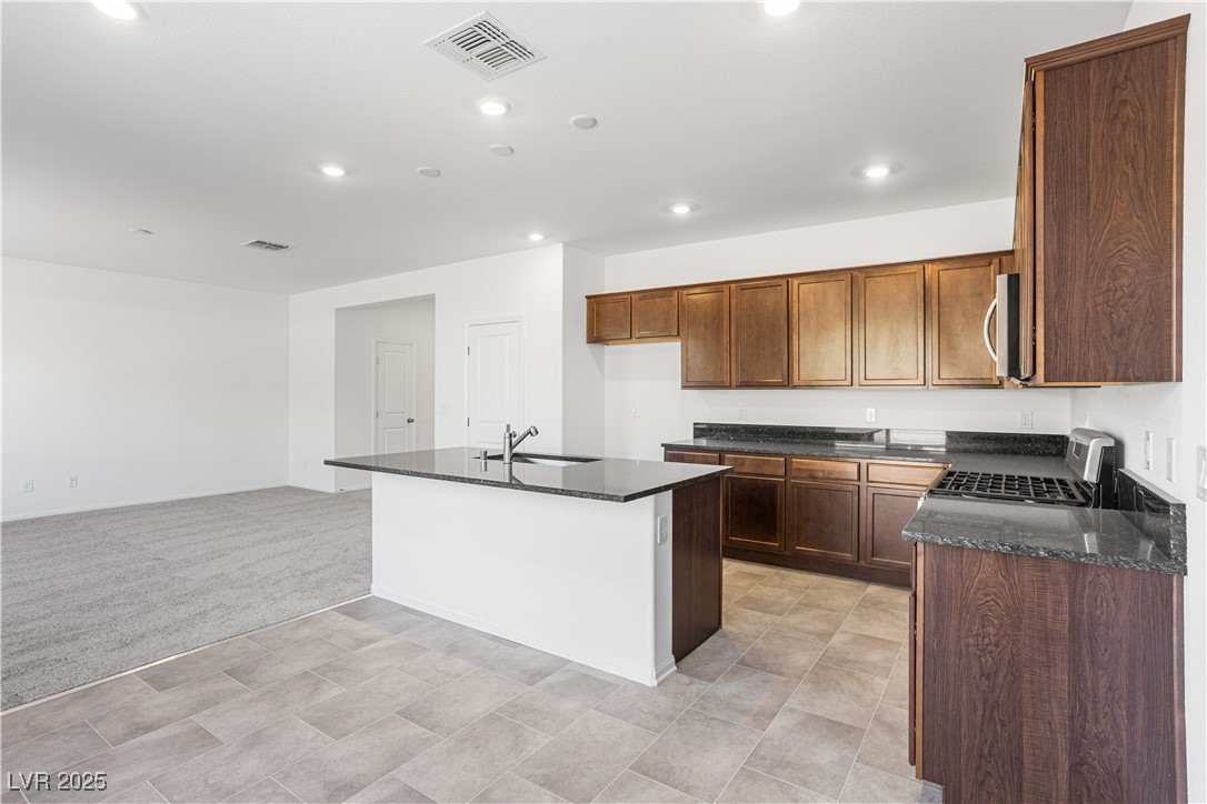 5670 Spring Trellis Street Las Vegas, NV 89113 - Photo 23 of 23 Kitchen featuring dark stone countertops, recessed lighting, a center island with sink, stainless steel appliances, and open floor plan