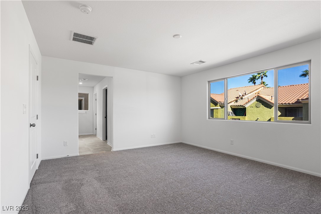 5670 Spring Trellis Street Las Vegas, NV 89113 - Photo 5 of 23 Empty room with light colored carpet and baseboards
