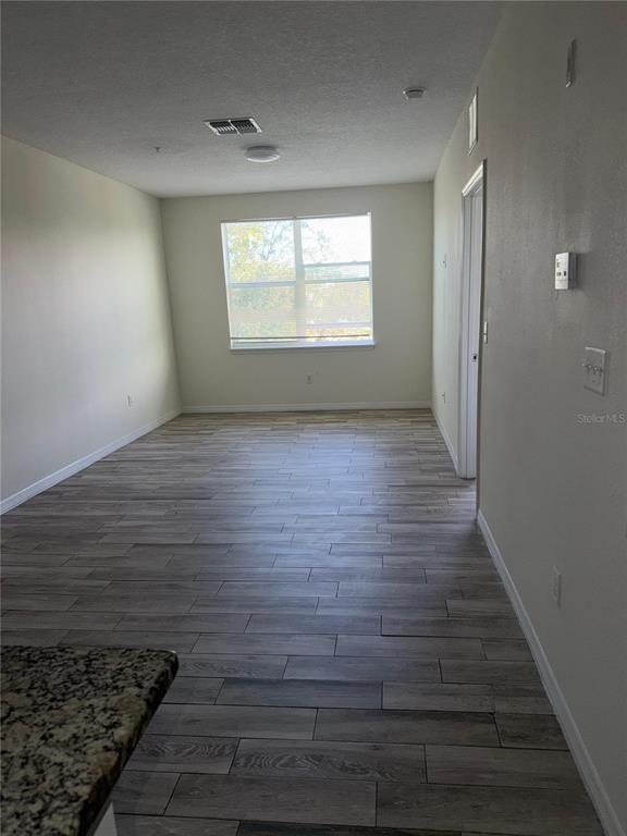 2121 McCoy Road, Unit 235 Orlando, FL 32809 - Photo 4 of 20 a view of an empty room with wooden floor and a window