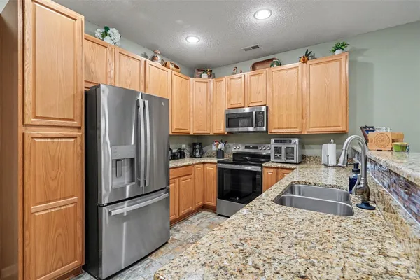 a kitchen with granite countertop a refrigerator stove and sink