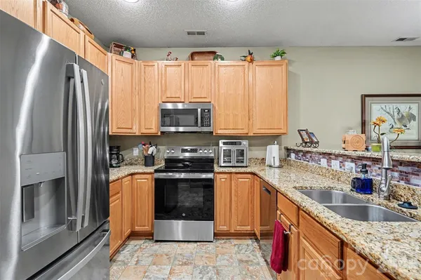 a kitchen with stainless steel appliances granite countertop a sink stove and refrigerator