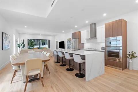 a kitchen with kitchen island stainless steel appliances a dining table chairs and wooden floor