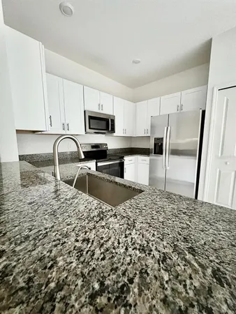 a kitchen with granite countertop a refrigerator and a stove top oven