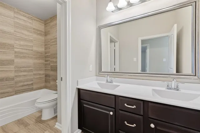 a bathroom with a granite countertop sink a toilet and a mirror