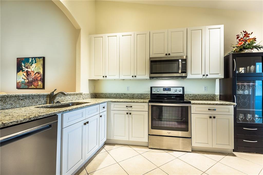 3800 Tripoli Boulevard, Unit 35 Punta Gorda, FL 33950 - Photo 10 of 44 a kitchen with granite countertop a stove top oven microwave and cabinets