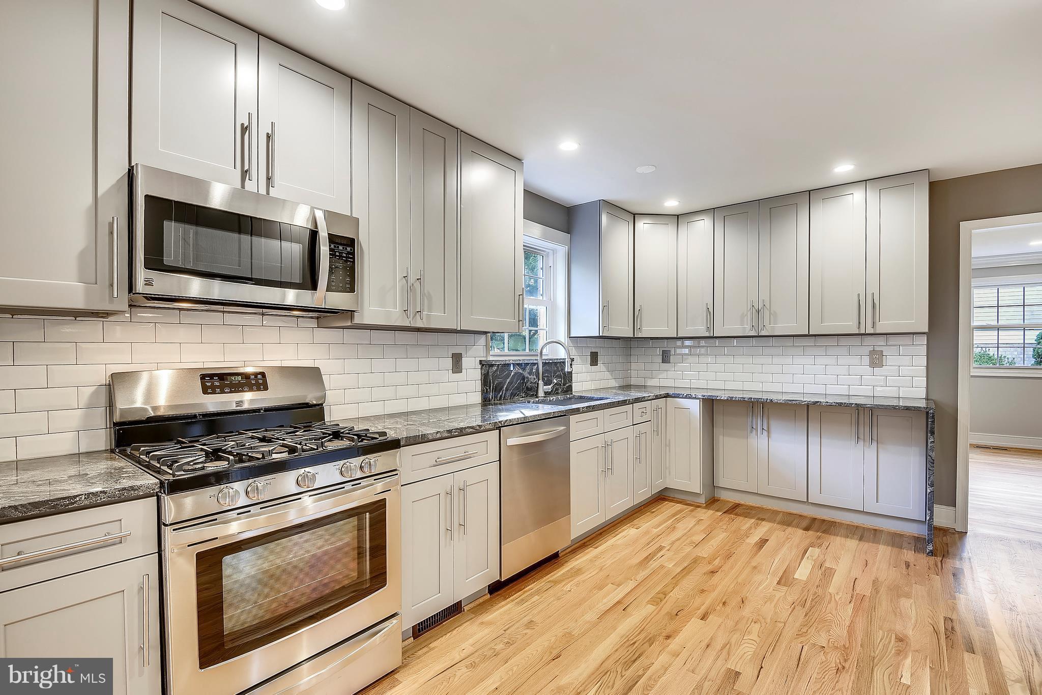 4017 Olney Laytonsville Road Olney, MD 20832 - Photo 2 of 28 a kitchen with granite countertop wooden floors stainless steel appliances and white cabinets