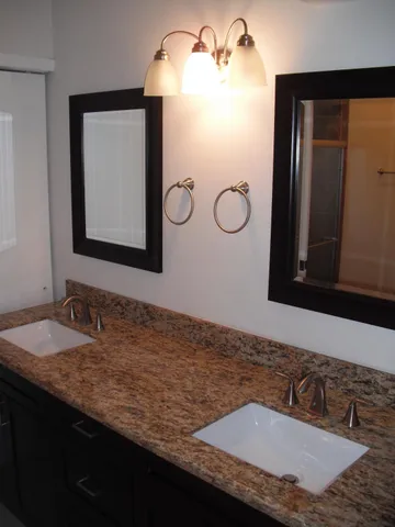 a bathroom with a granite countertop sink and a mirror