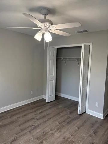 an empty room with wooden floor fan and windows