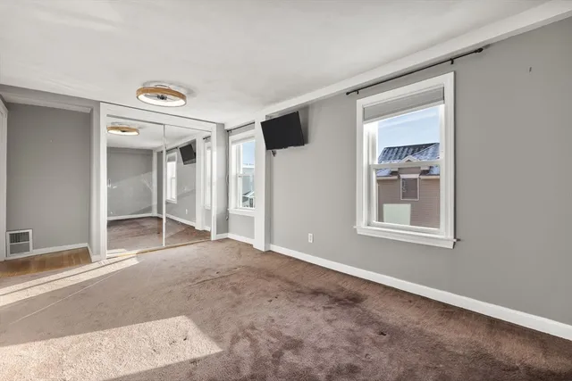 a view of an empty room with closet and a window