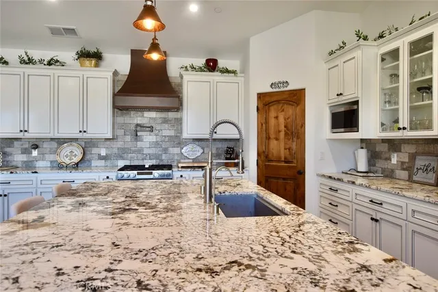 a kitchen with granite countertop a stove a sink dishwasher and wooden cabinets with wooden floor
