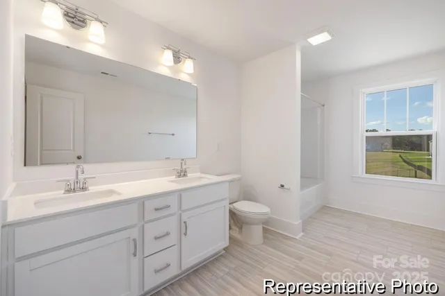 a spacious bathroom with a double vanity sink a toilet and a mirror