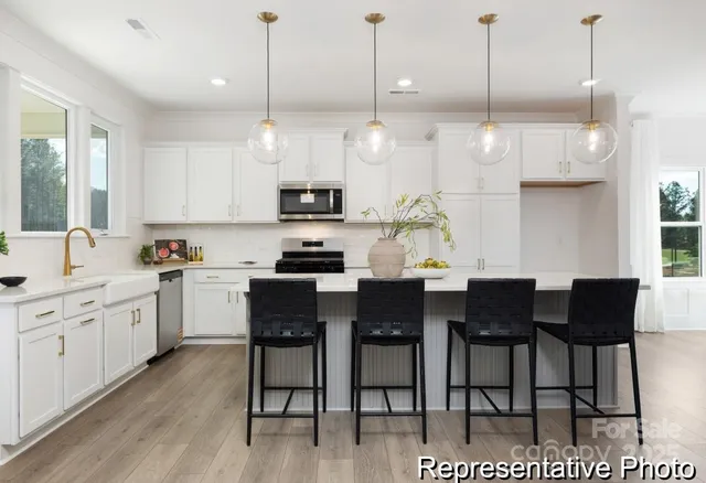 a kitchen with stainless steel appliances kitchen island granite countertop a sink a stove a dining table and chairs