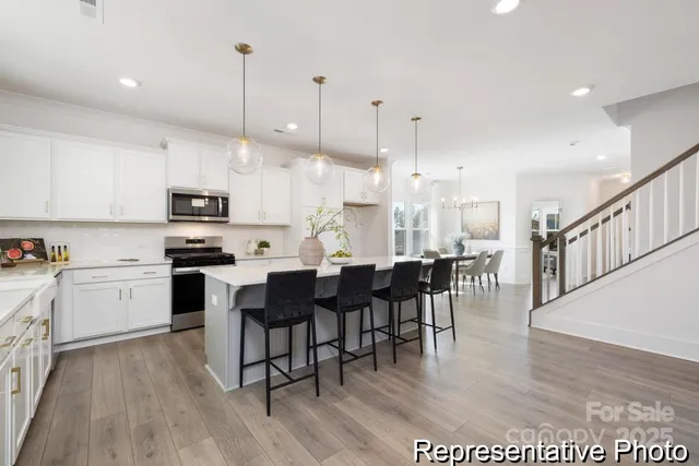 a large kitchen with cabinets chairs and wooden floor