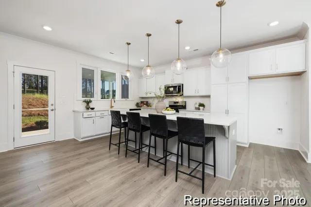 a open kitchen with stainless steel appliances granite countertop a stove a refrigerator a kitchen island a sink dishwasher and a dining table with wooden floor