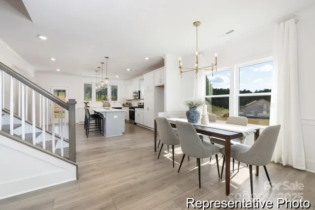 a view of a dining room and livingroom with furniture wooden floor a rug a flat screen tv a painting and a chandelier