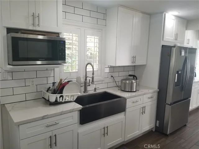 a kitchen with stainless steel appliances a sink a stove a microwave a refrigerator and cabinets