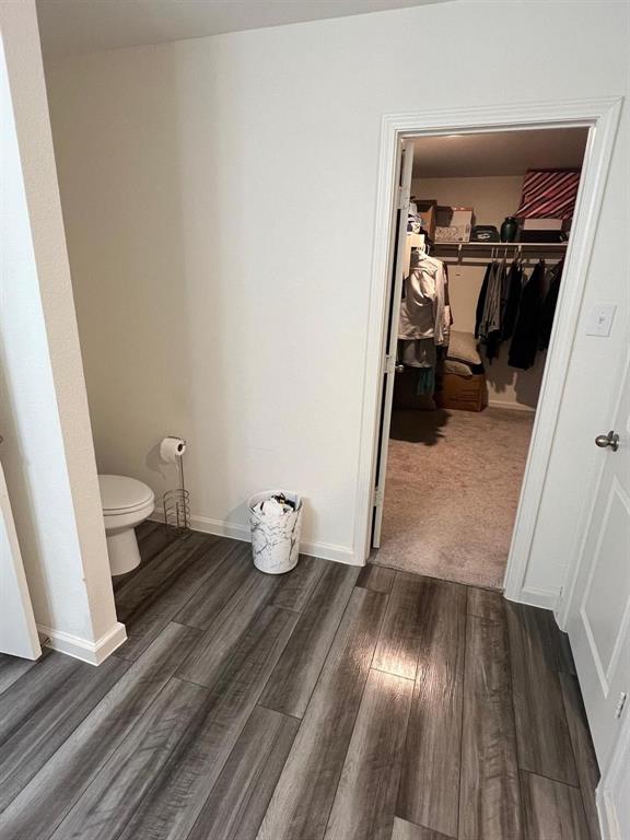 1908 Marquette Road Princeton, TX 75407 - Photo 12 of 14 Wood-finish plank flooring in a neutral tone, featuring white baseboards, a white wall, and a doorway leading to a carpeted closet space