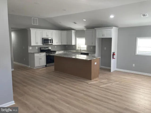 a large kitchen with stainless steel appliances granite countertop a stove a sink and a refrigerator