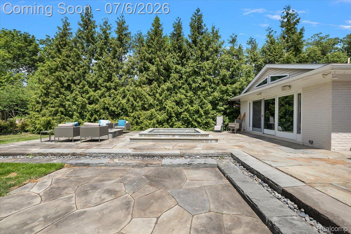 1051 Devonshire Road Grosse Pointe, MI 48230 - Photo 86 of 98 Expansive flagstone patio area featuring a built-in fire pit, multiple seating areas, a decorative rock channel, and direct access to the home through large sliding glass doors
