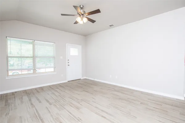 a view of empty room with wooden floor and fan