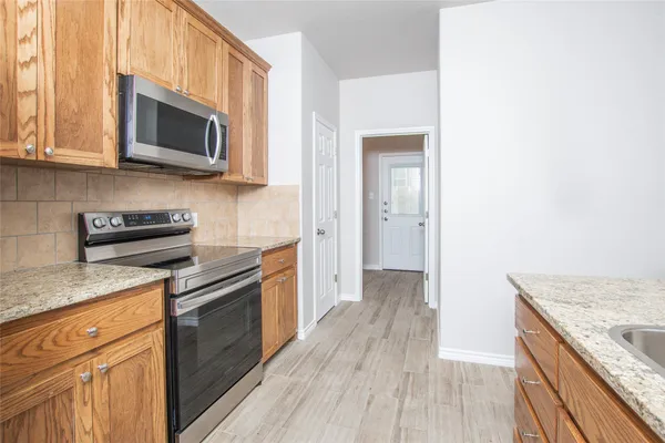 a kitchen with stainless steel appliances granite countertop wooden cabinets a stove top oven a sink and dishwasher