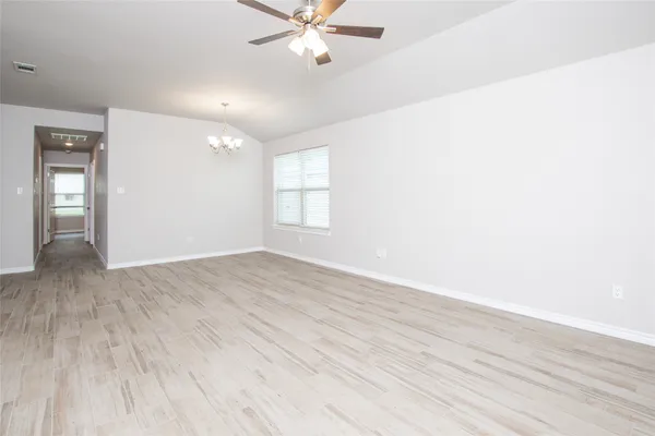 an empty room with wooden floor fan and windows