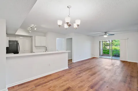 a view of a kitchen with a dishwasher a kitchen island white cabinetry and wooden floor