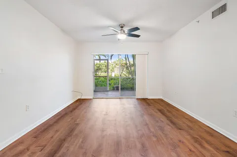 an empty room with wooden floor fan and windows