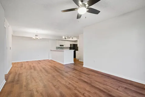 a view of kitchen and empty room with wooden floor