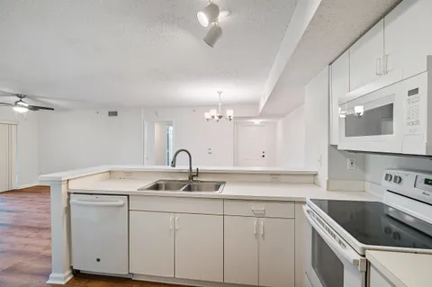 an empty room with wooden floor ceiling fan and windows