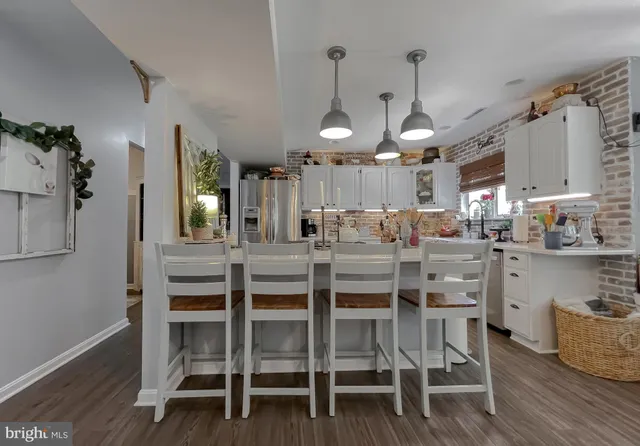 a kitchen with stainless steel appliances a dining table chairs and white cabinets