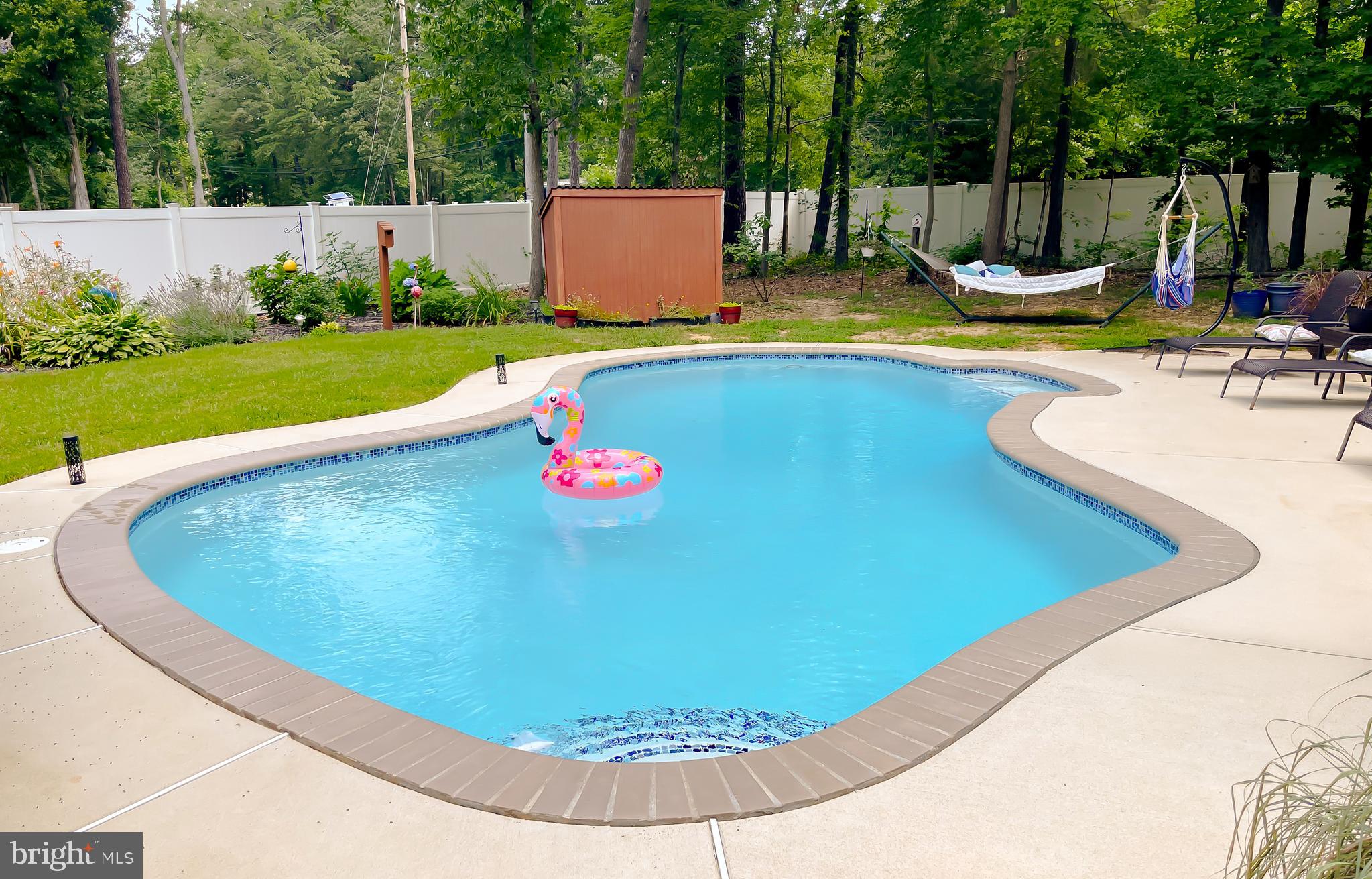 22338 White Oak Road Leonardtown, MD 20650 - Photo 61 of 66 a view of a swimming pool with a yard and trees in the background