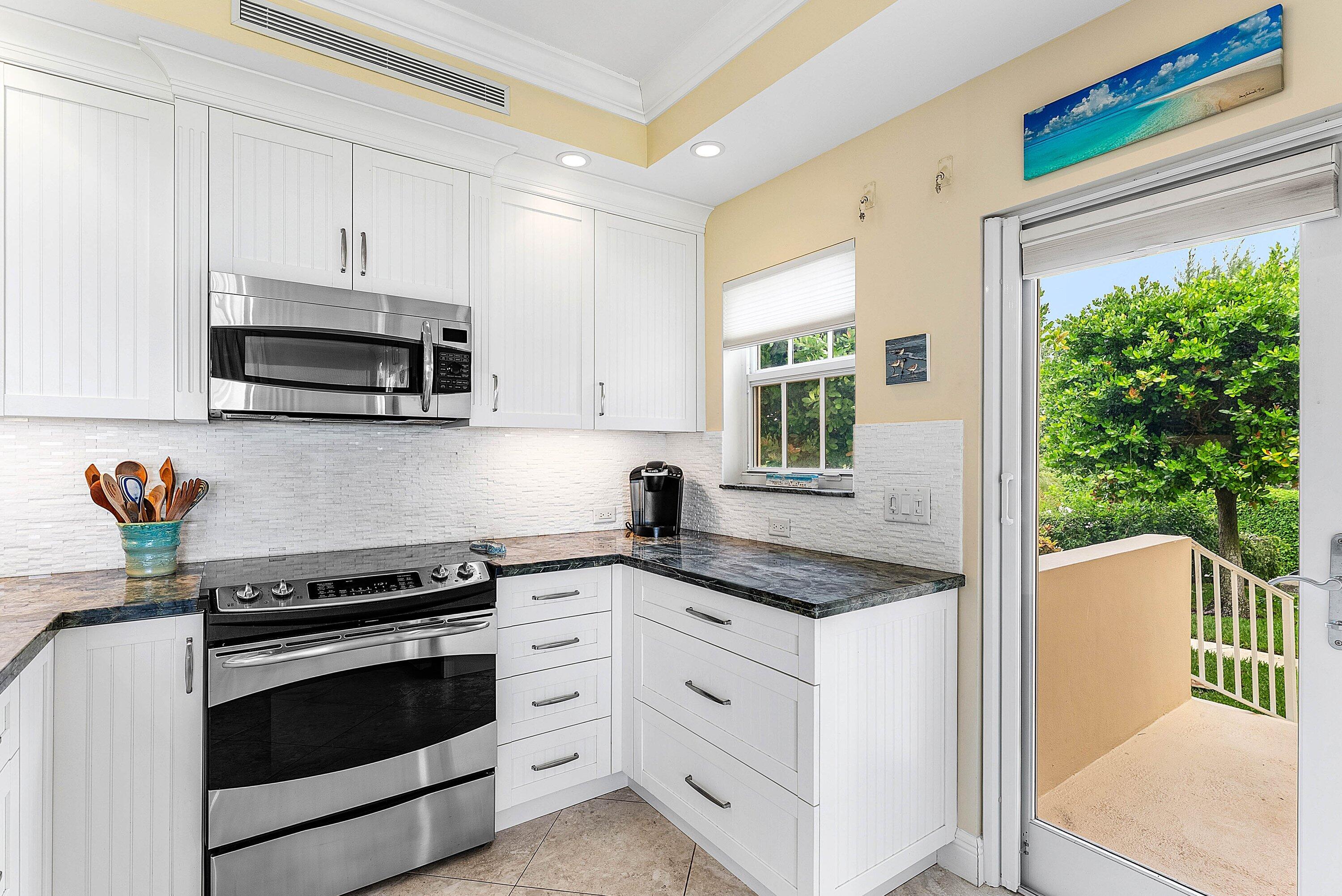 2103 South Ocean Boulevard, Unit 4B Delray Beach, FL 33483 - Photo 11 of 46 a kitchen with granite countertop a stove a sink and a microwave