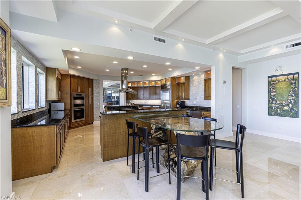 295 Grande Way, Unit PH2 Naples, FL 34110 - Photo 8 of 45 a kitchen with stainless steel appliances kitchen island granite countertop a table and chairs in it
