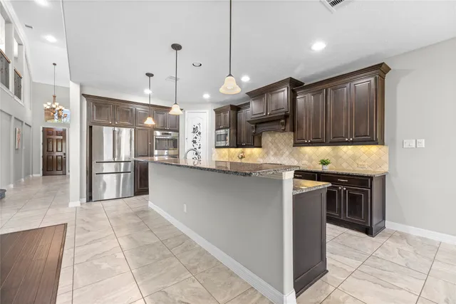a kitchen with kitchen island a counter top space a sink stainless steel appliances and cabinets