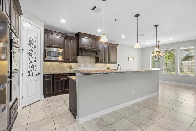 a large kitchen with stainless steel appliances kitchen island granite countertop a refrigerator a stove a sink and a microwave