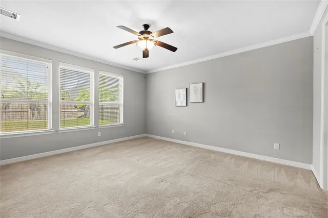 an empty room with windows and chandelier fan