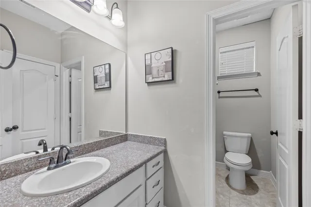 a bathroom with a granite countertop toilet a sink and a mirror