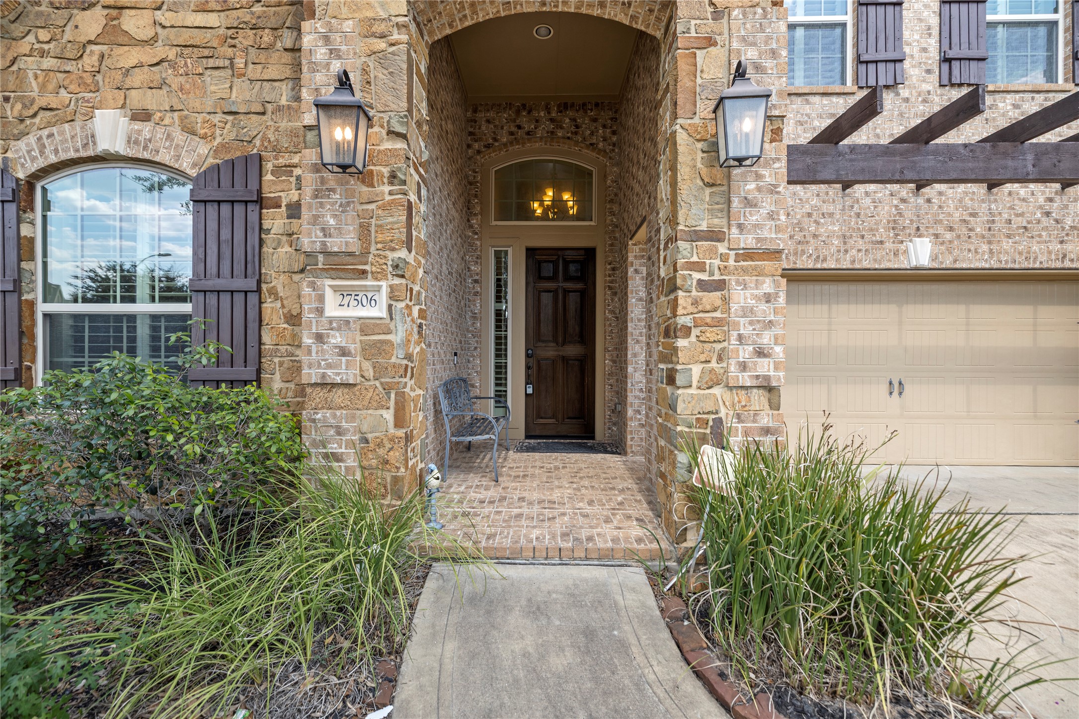 27506 Windcrest Key Lane Fulshear, TX 77441 - Photo 3 of 30 a view of a brick house with potted plants and a table and chairs