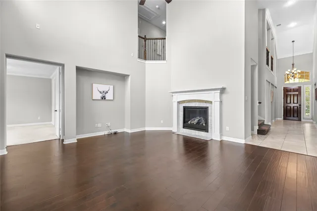 an empty room with wooden floor fireplace and windows