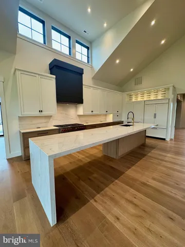 a large white kitchen with stainless steel appliances granite countertop a sink and a stove