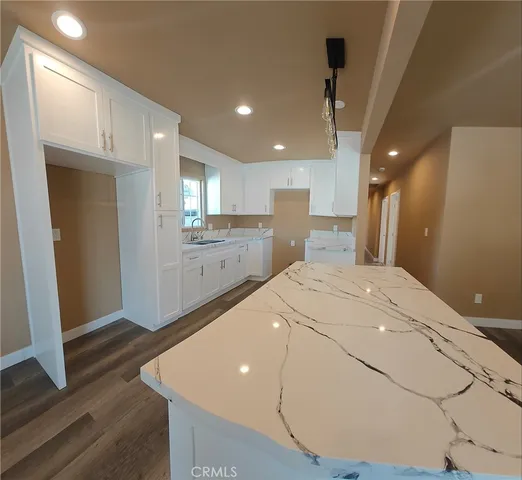a large white kitchen with a sink a refrigerator and a stove top oven