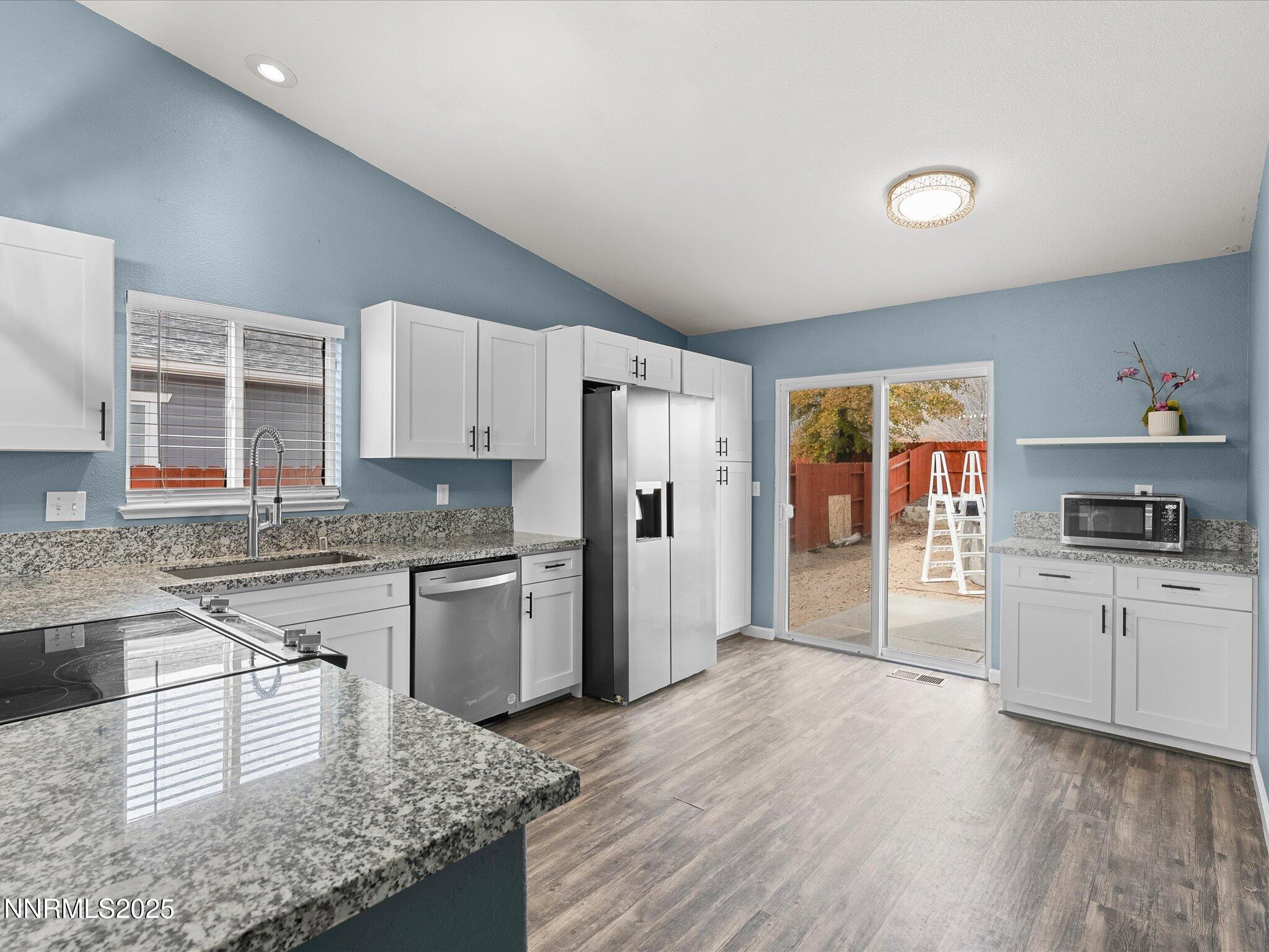 17795 Georgetown Drive Reno, NV 89508 - Photo 5 of 41 a kitchen with granite countertop a stove top oven a sink dishwasher a refrigerator and white cabinets with wooden floor