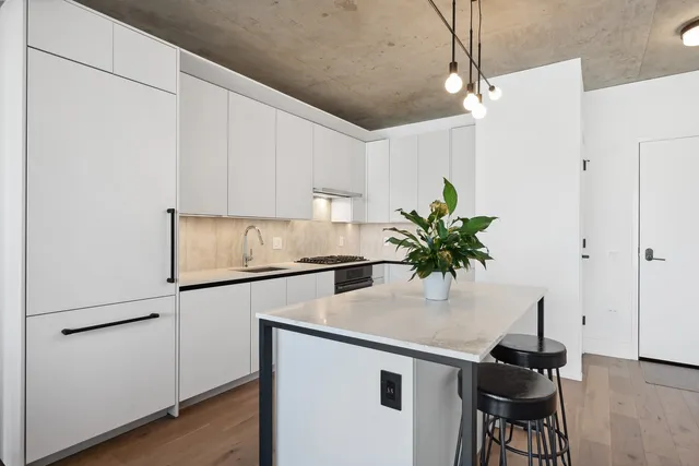 a kitchen with stainless steel appliances granite countertop a stove a sink a refrigerator and white cabinets with wooden floor