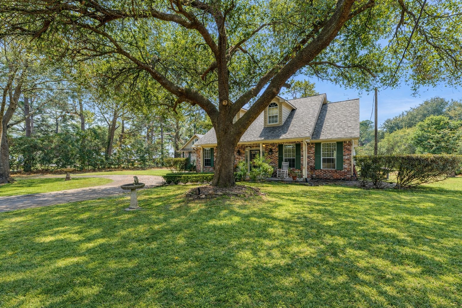 22625 Tomball Cemetery Road Tomball, TX 77377 - Photo 2 of 32 Charming brick home with a welcoming front porch, nestled under a large, mature tree. The spacious yard features manicured greenery, offering a serene and private setting. Perfect for enjoying outdoor relaxation and entertaining.